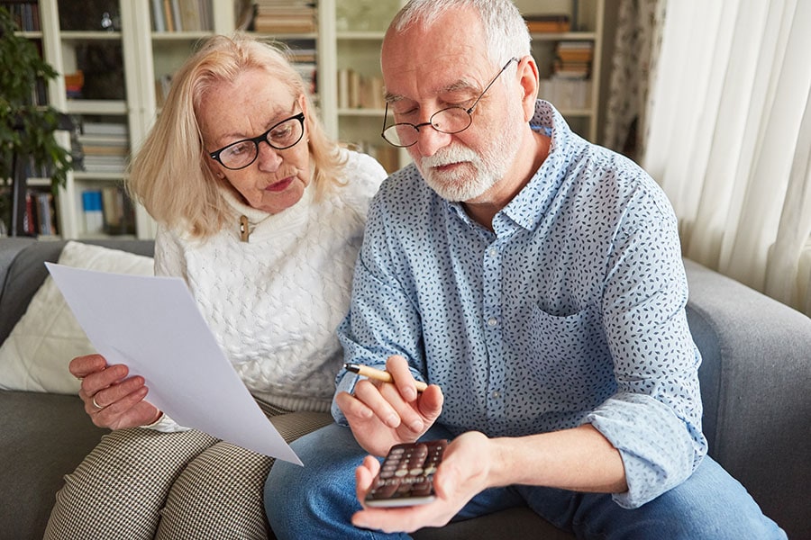 Senioren mit Taschenrechner berechnen Kosten der Finanzierung von Pflege
